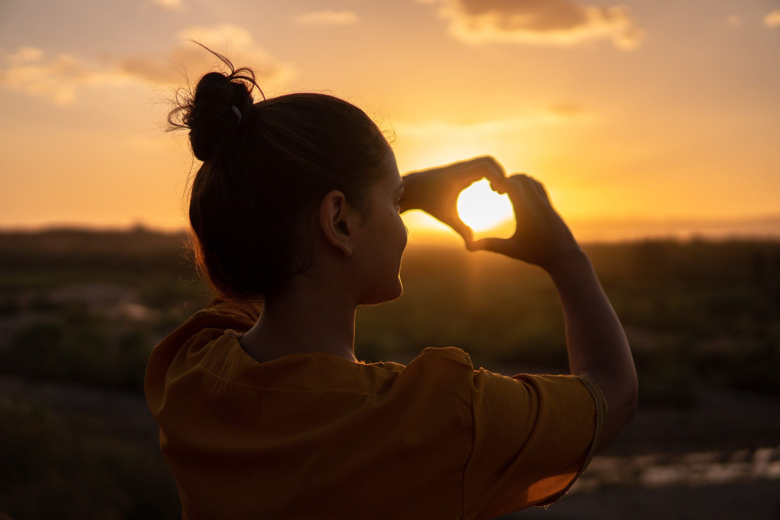 woman making a heart towards the sky