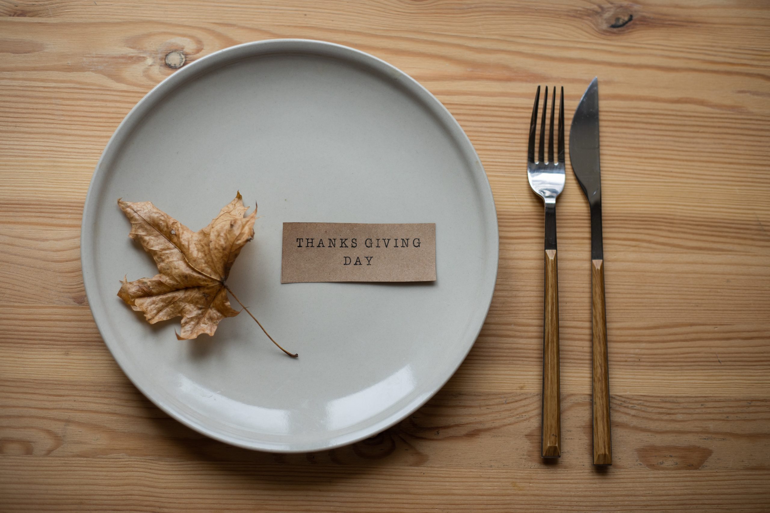 Plate and utensils on a brown table, with a thanksgiving note