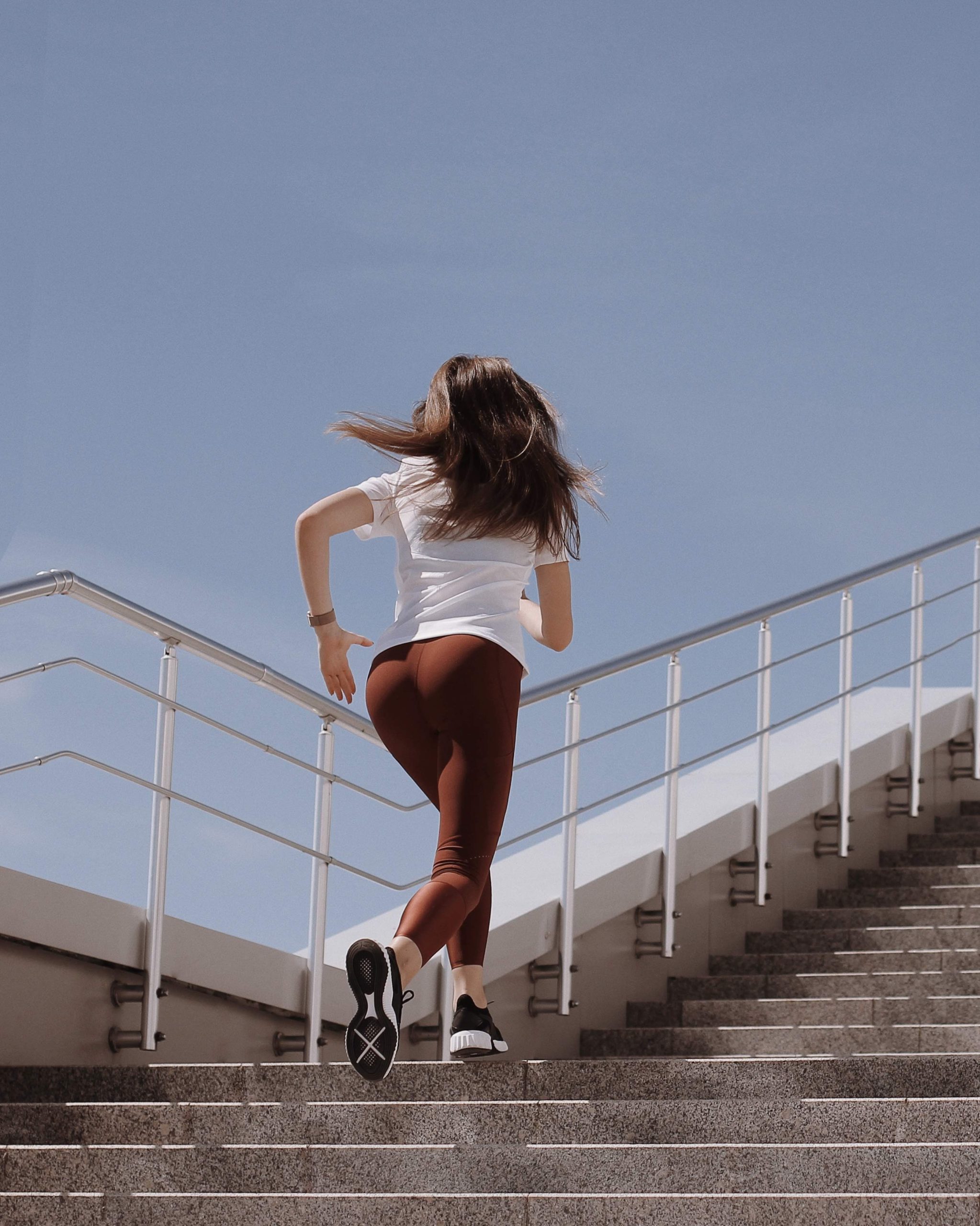 Woman wearing sports attire - running up the stairs